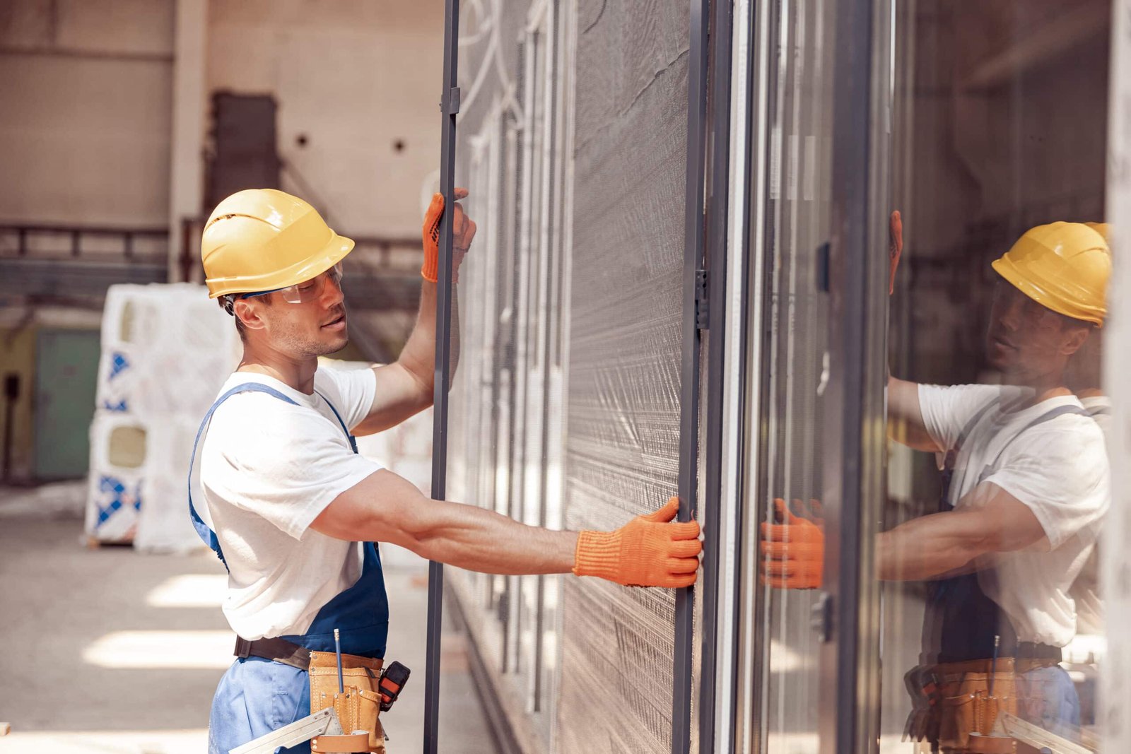 Male worker installing sliding glass door at constriction site