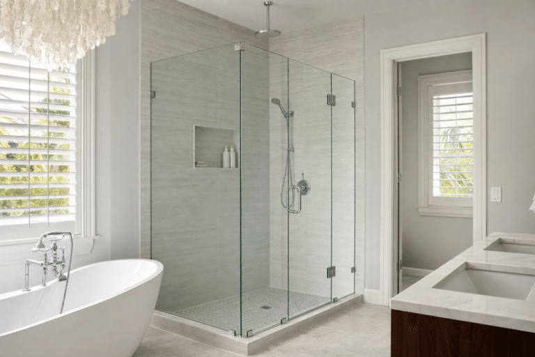 Modern bathroom with a glass-enclosed shower, a white freestanding bathtub, double sinks, and natural light from shuttered windows.