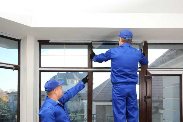 Construction workers repairing window in house