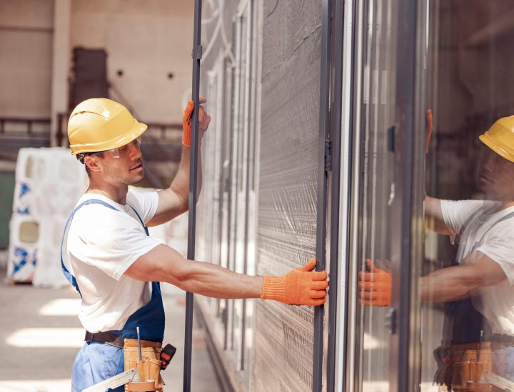 Male worker installing sliding glass door at constriction site